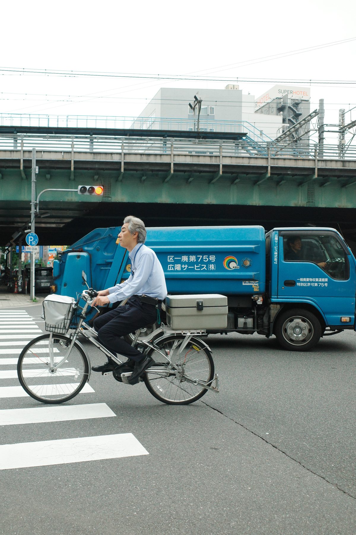 A man cycling past a blue truck