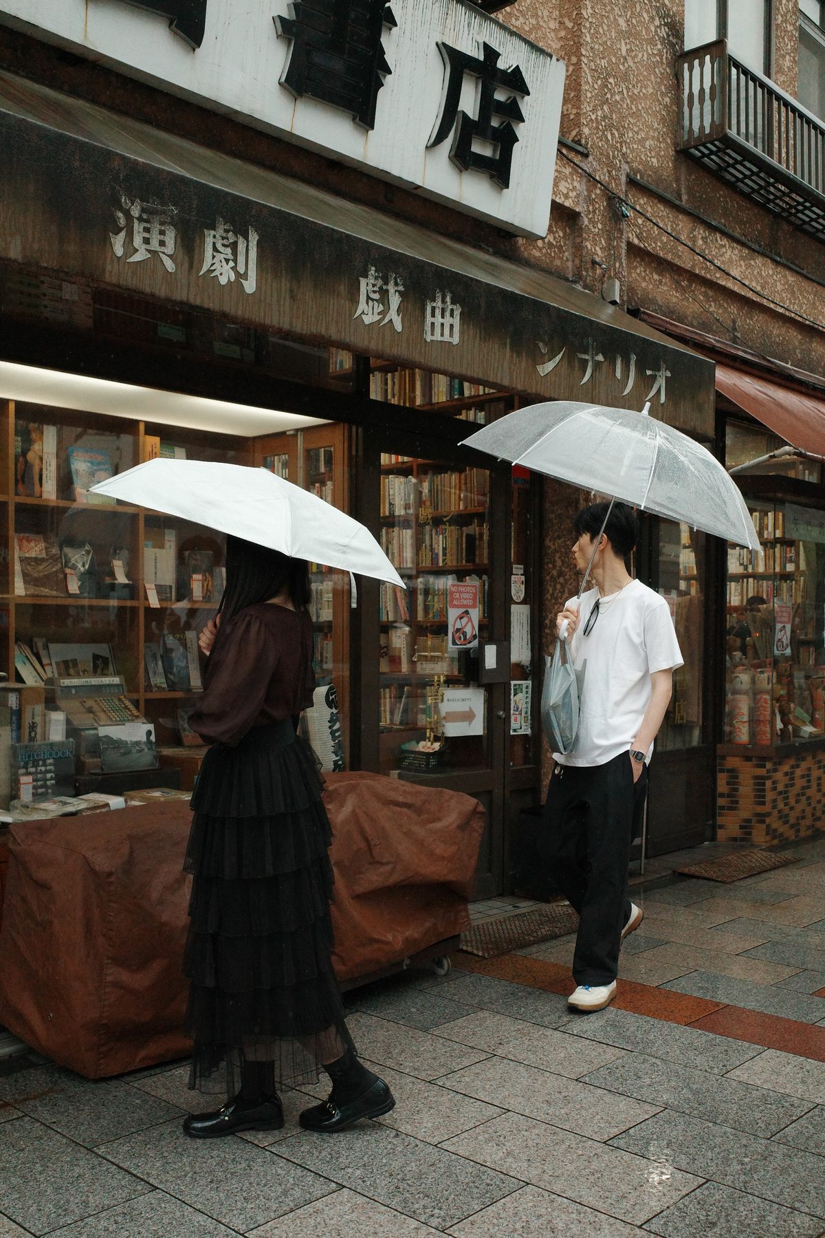 Two people browsing books under umbrellas
