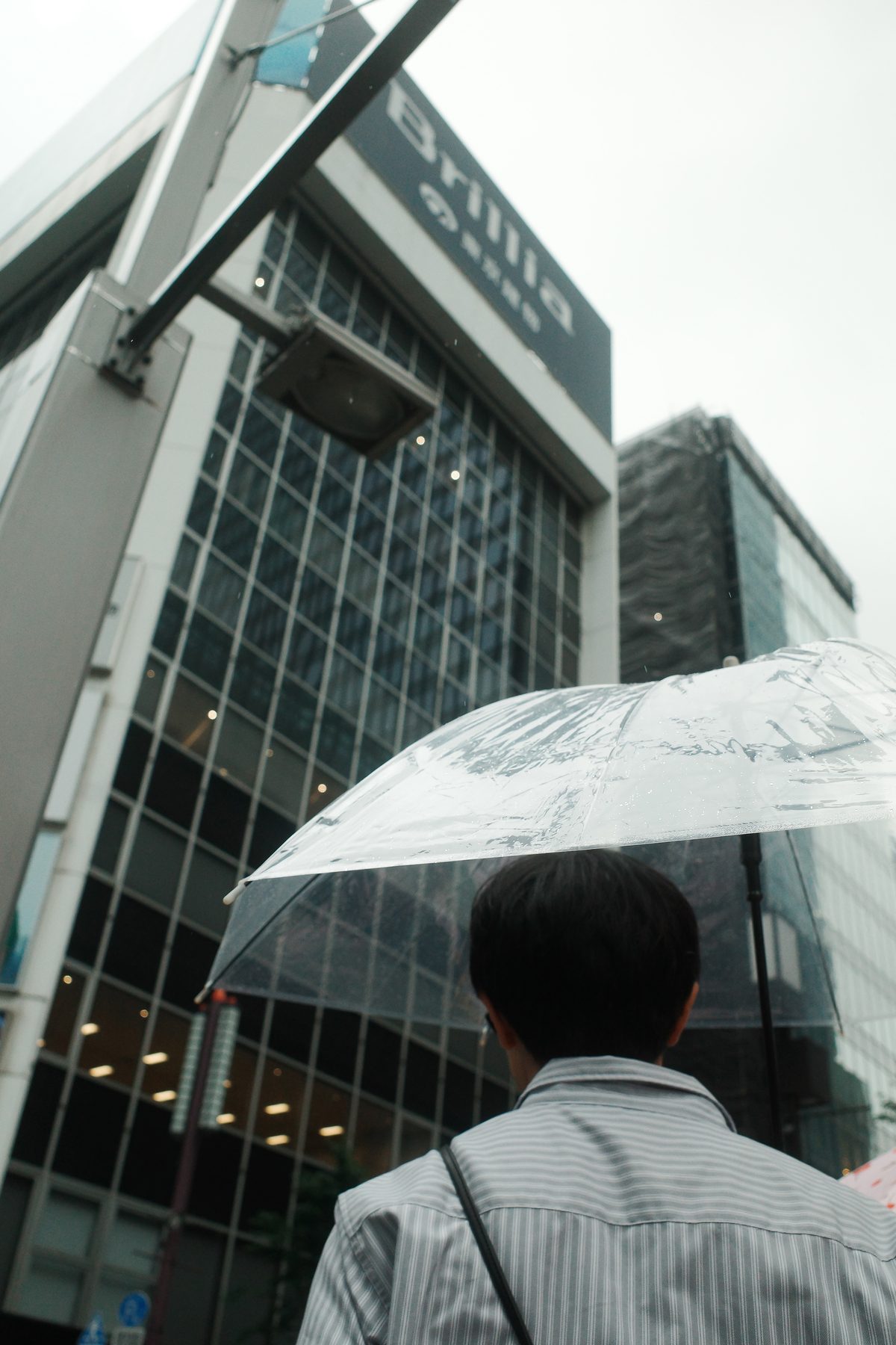 A man under an umbrella by an office tower