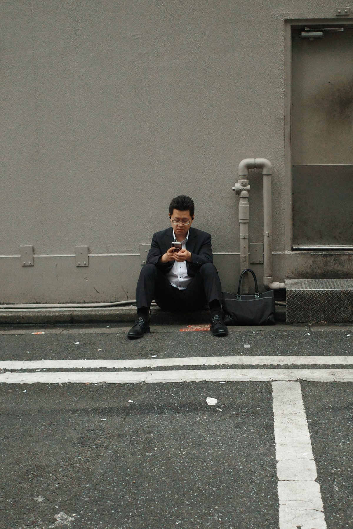 A man in a suit sitting on the pavement