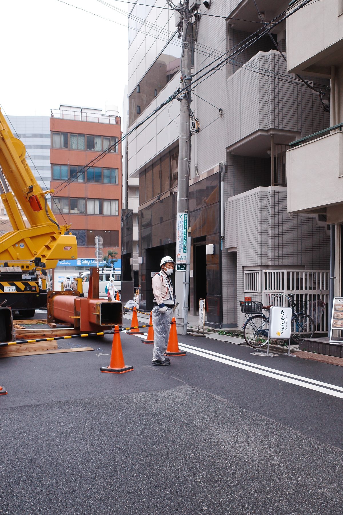 A crane and a worker in a side street