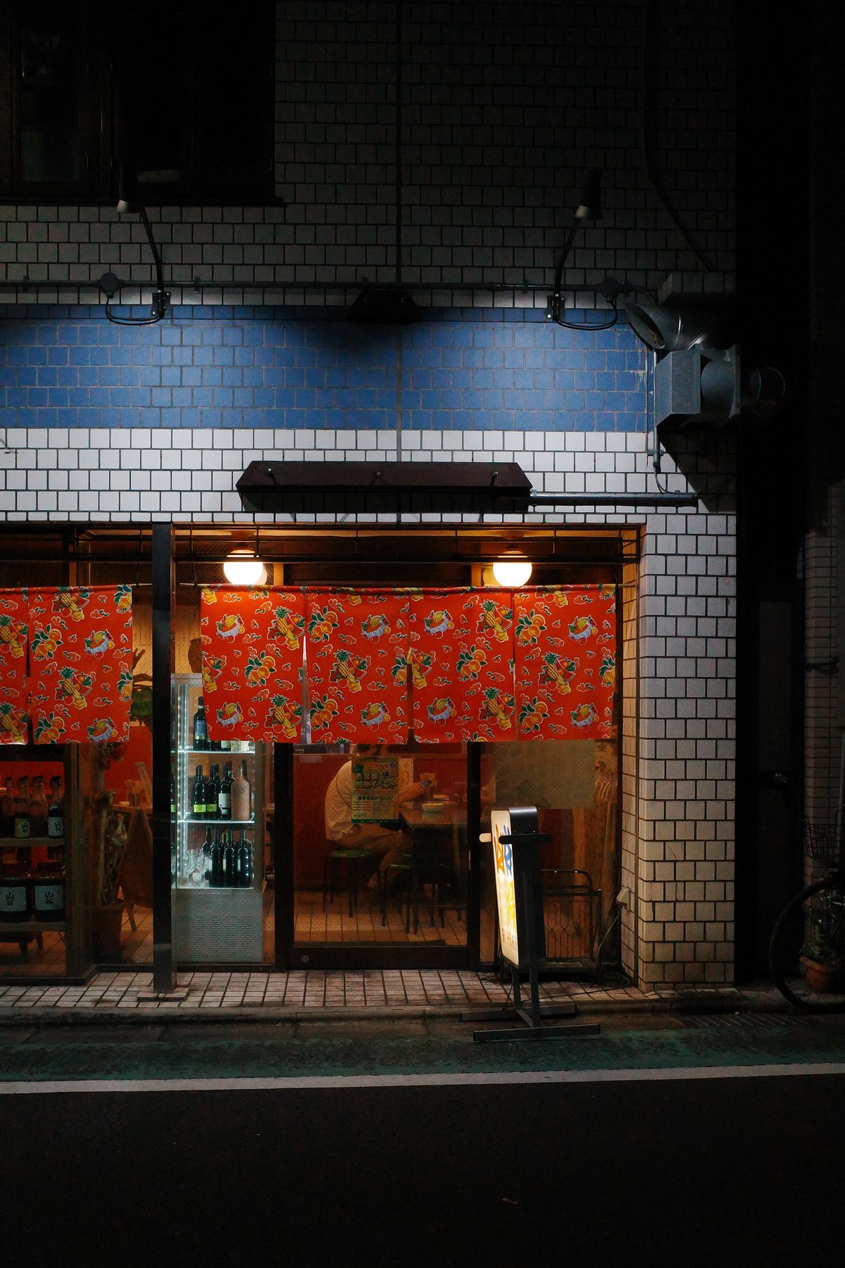 A restaurant behind red noren at night