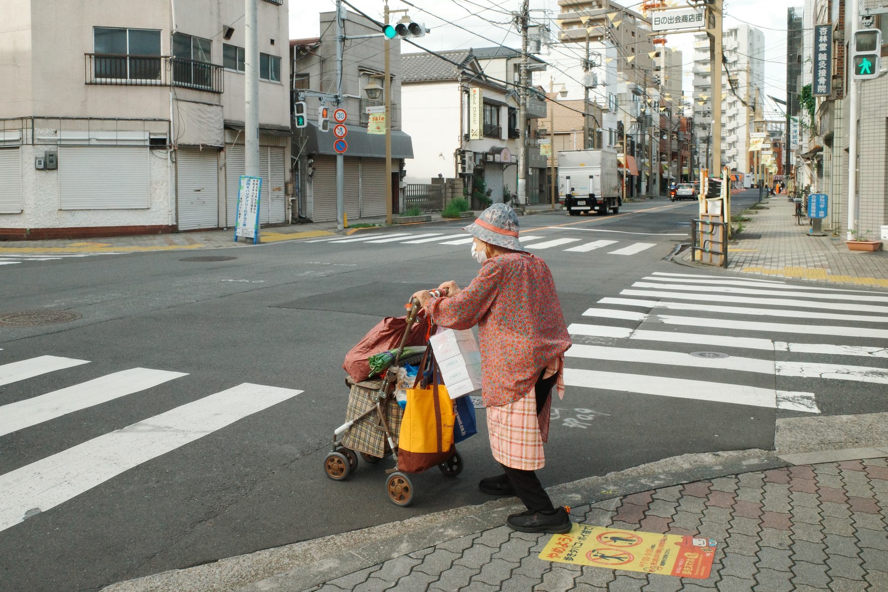 An old woman crossing with her trolley