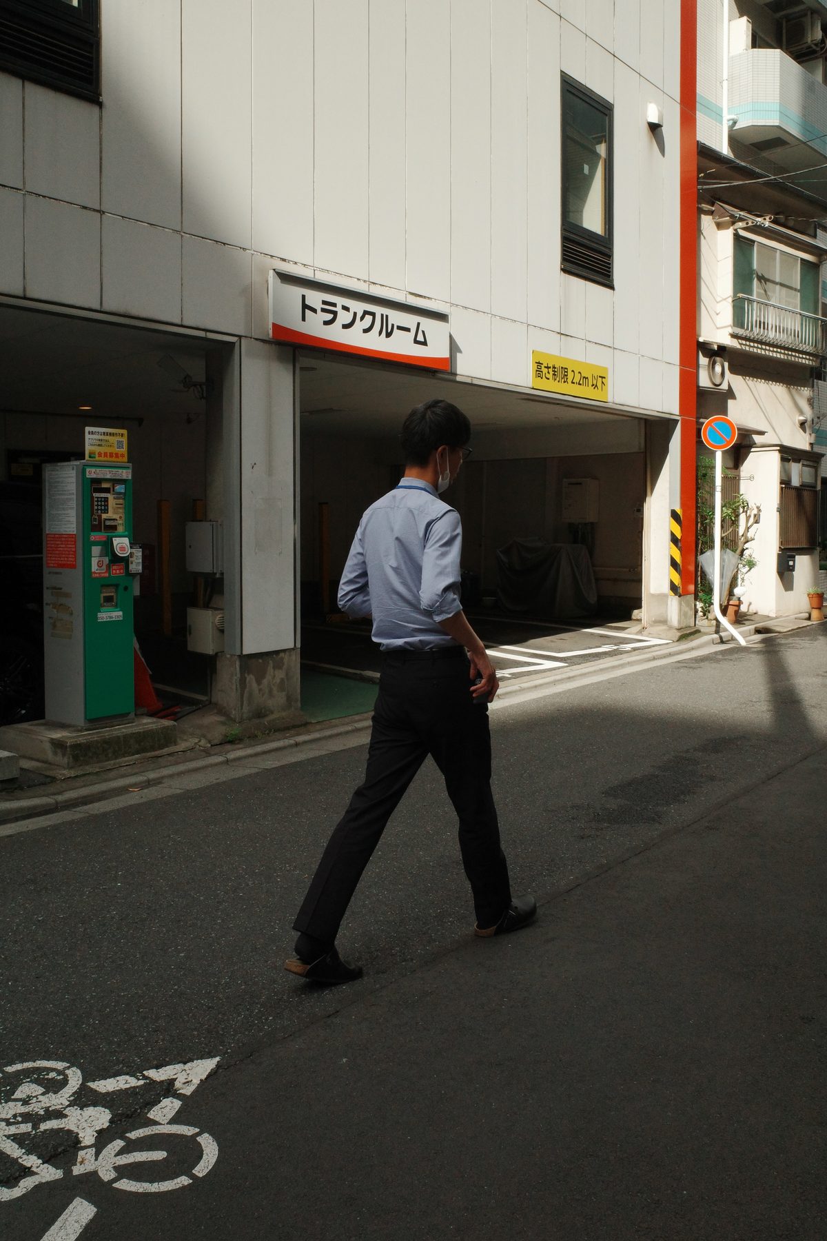 A man in a white shirt walking past a garage