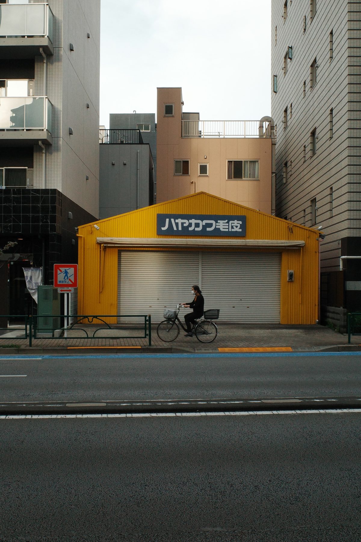 A cyclist passing a yellow shopfront