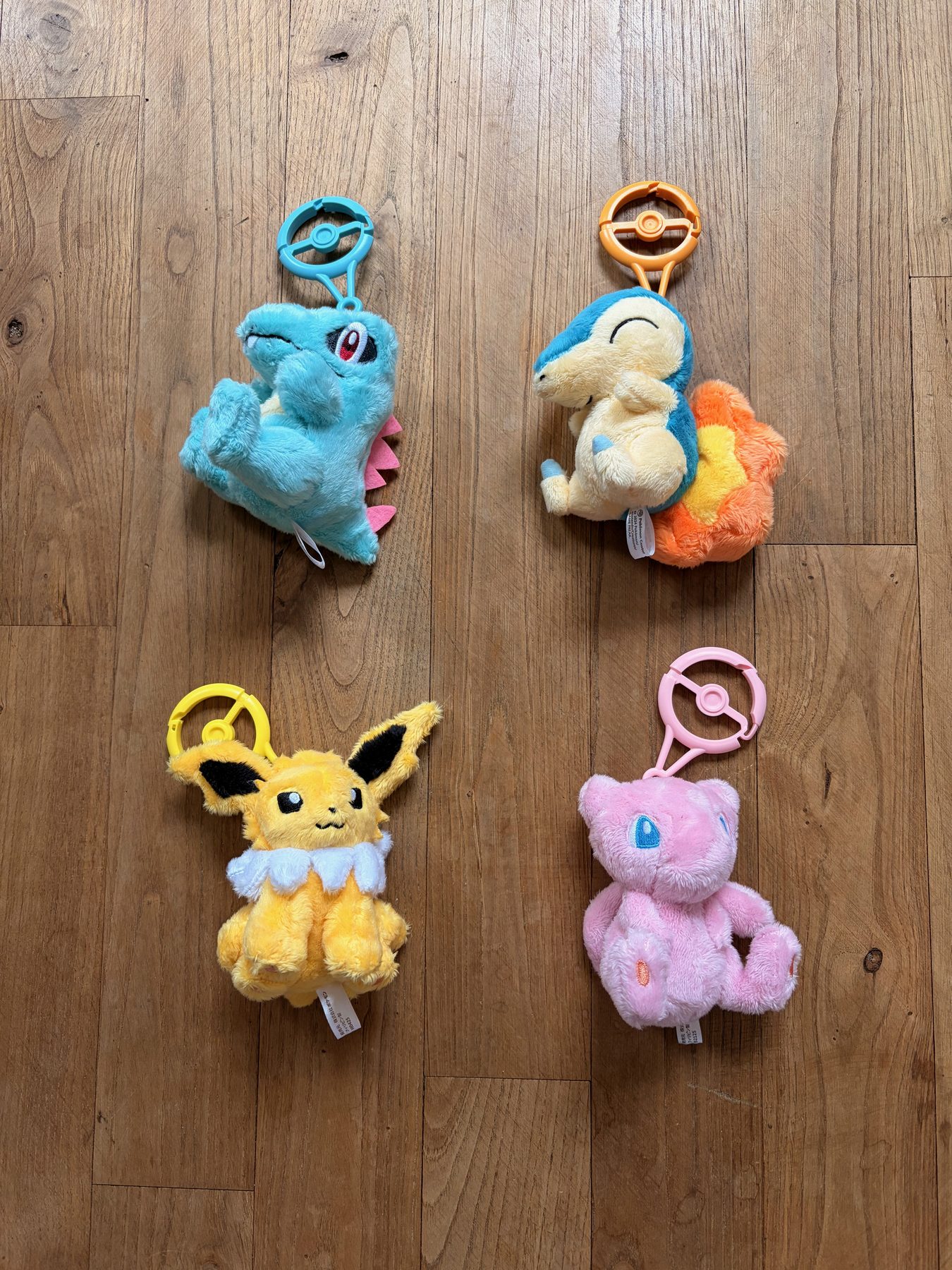 Four small Pokémon plushes on a wooden floor