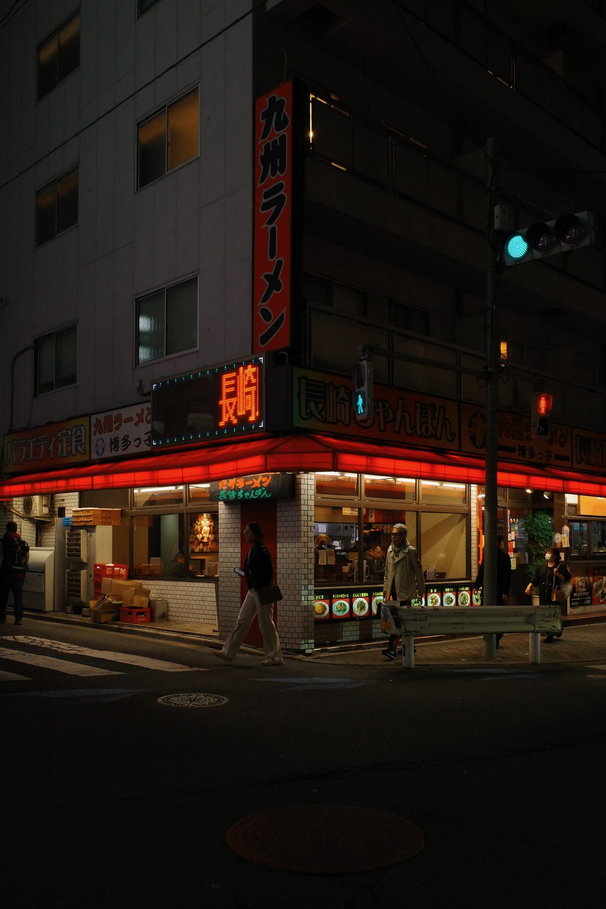 A ramen restaurant on a street corner at night