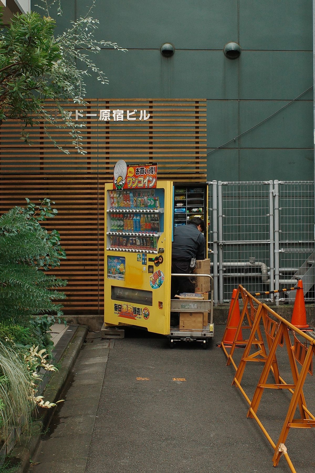 A yellow vending machine behind a construction barrier