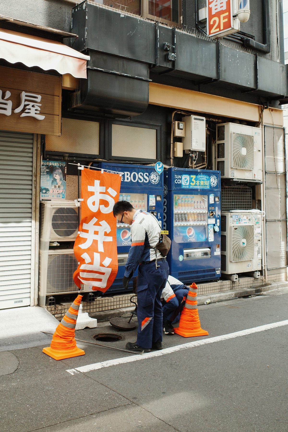 A bento sign and workers by a vending machine