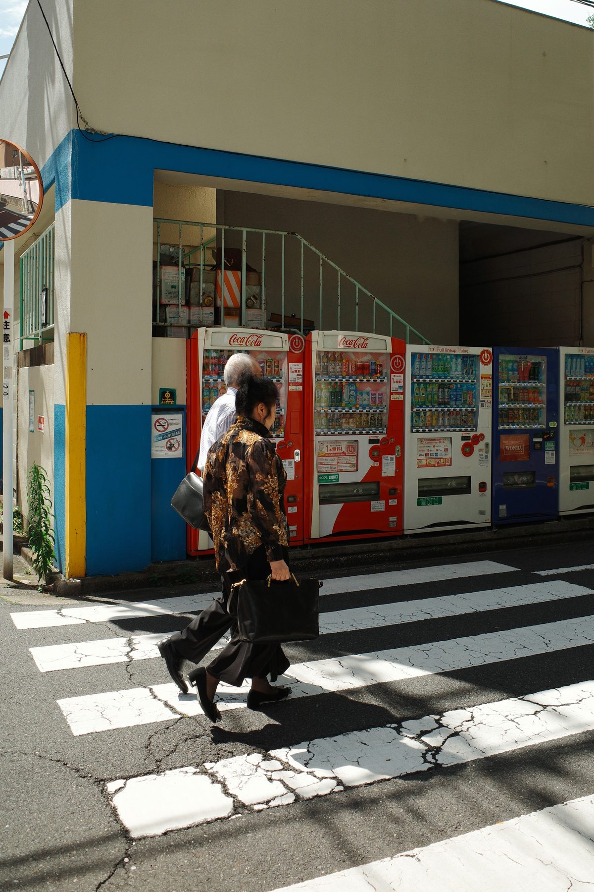 Two people crossing past vending machines