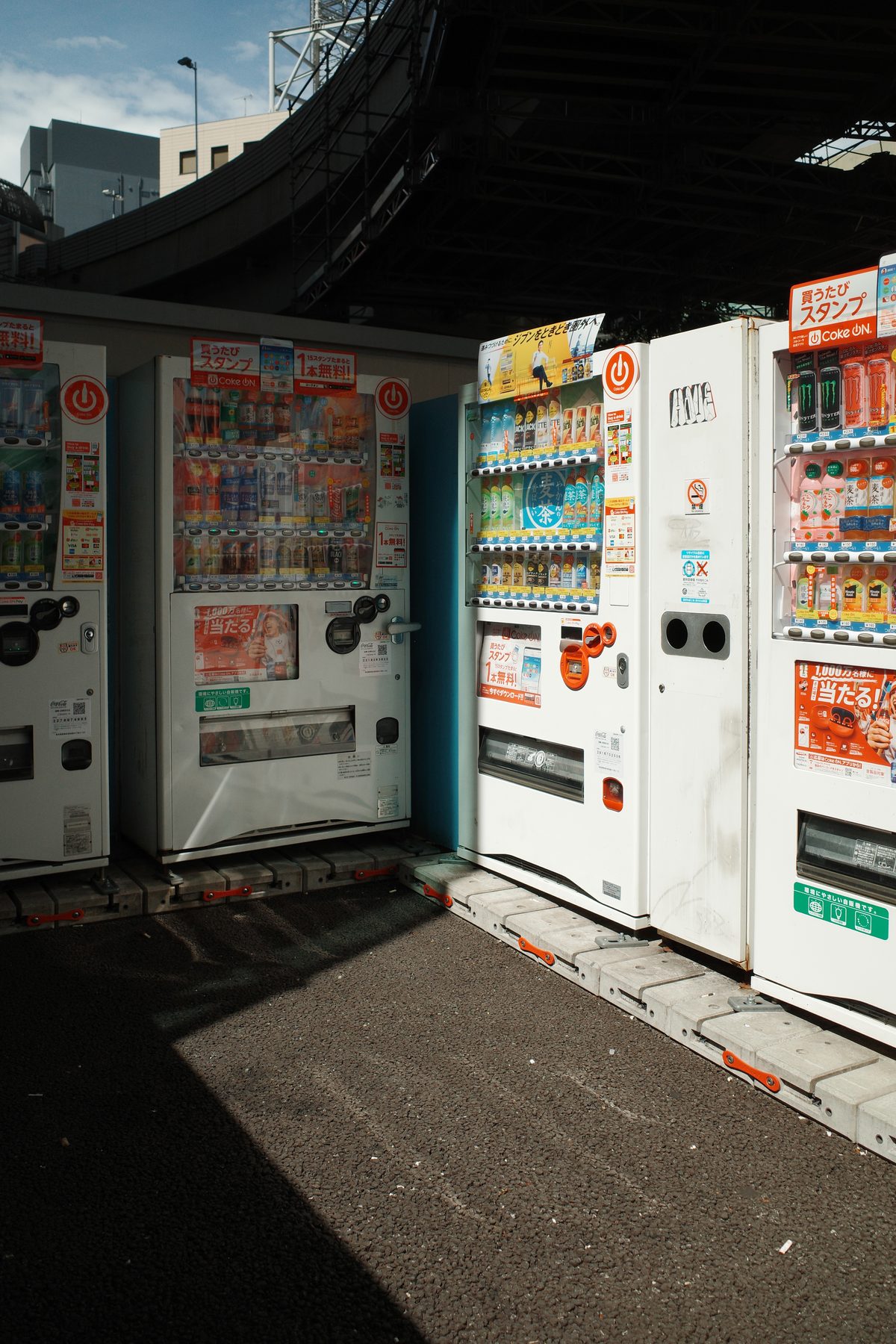 A row of vending machines under a bridge
