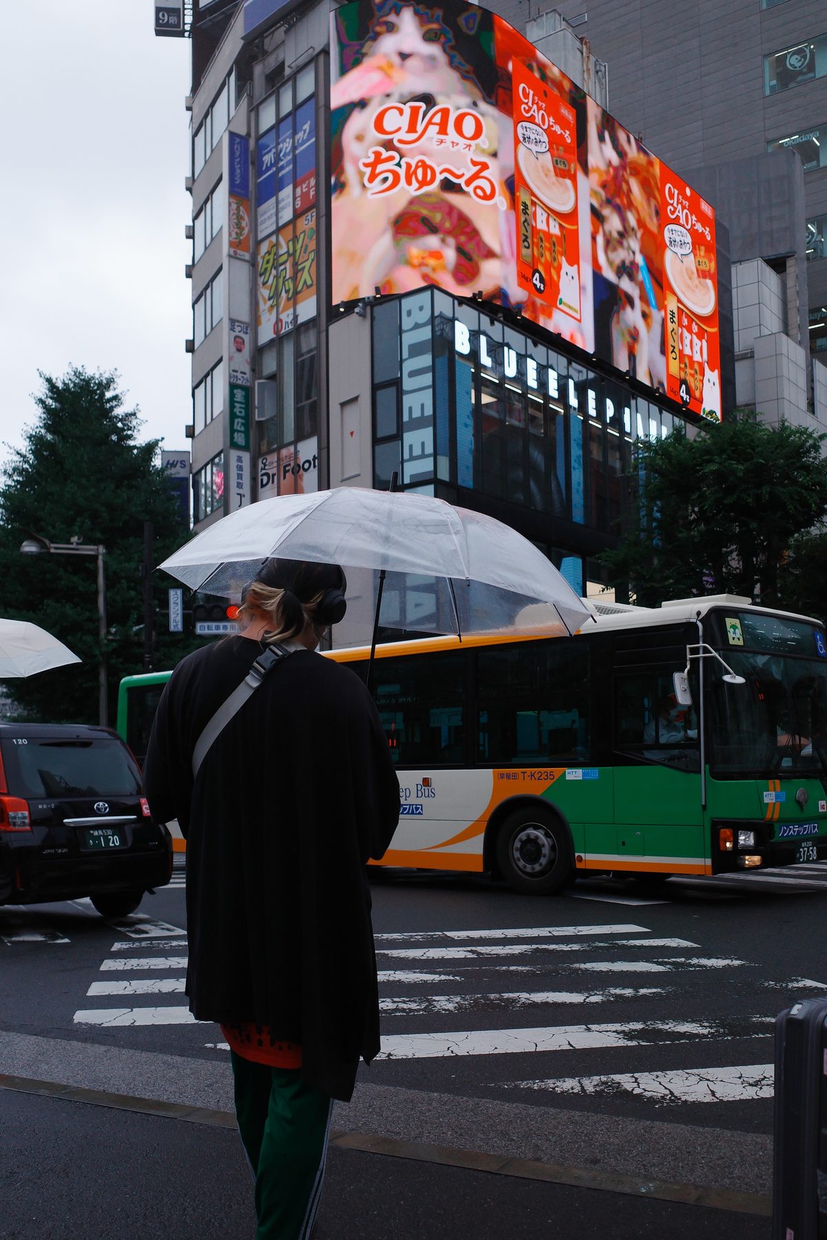 A green bus and a woman with an umbrella